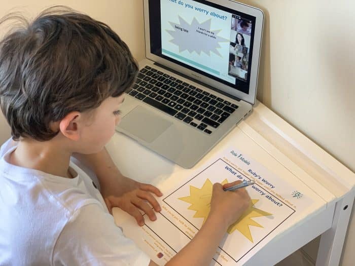 child at laptop with worksheet