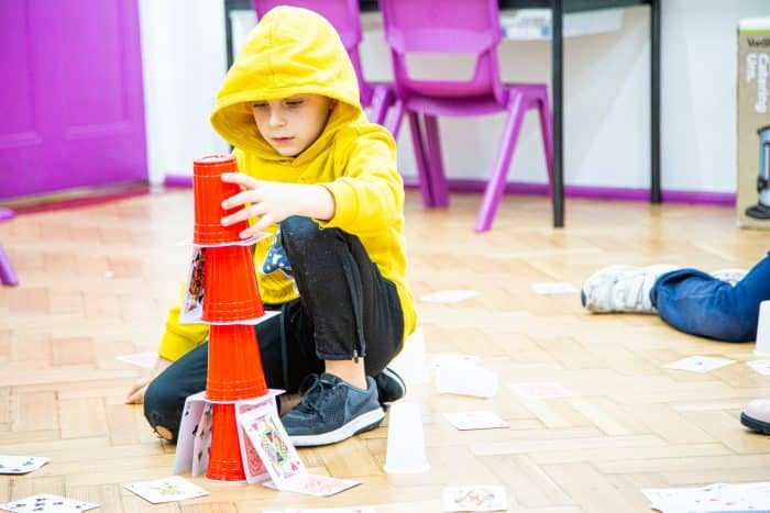 boy in yellow jacket stacking cups